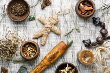 Voodoo bebeği, sihirli bitkiler ve eski bir masanın üzerindeki büyücülük özellikleri.