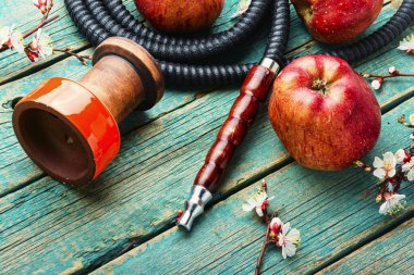 Elma aromalı tütünün üzerinde nargile tüttürüyor.