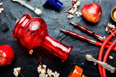 Elma aromalı tütünün üzerinde nargile tüttürüyor.