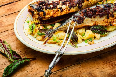 Ahşap mutfak masasında nefis fırında uskumru balığı. Kaynamış patatesli kızarmış uskumru.