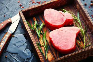 Mutfak masasında taze çiğ ton balığı bifteği ve tarhun.