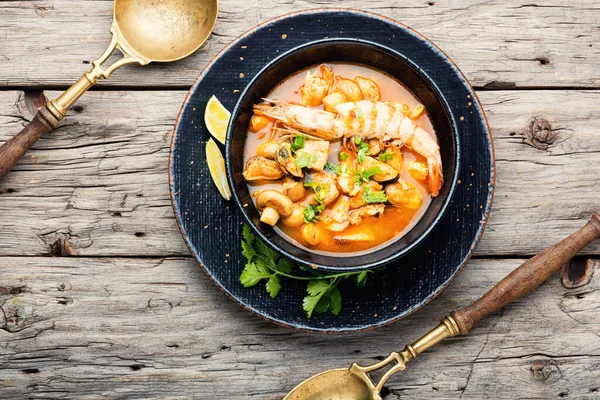 Spicy thai soup tom yam in plate on rustic wooden background
