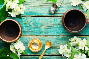Çiçek açan yasemin bitki çayı. Ahşap arka planda kil çay fincanları..