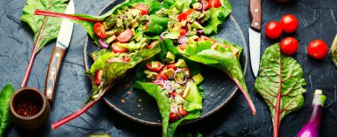 Avokado salatası, pazı yapraklarında sarımsak soslu domates. Tabakta vitamin salatası. Sağlıklı salata.