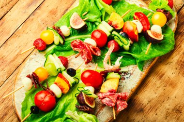 Açık büfe karides, jamon, meyve ve sebzeler. Bambu şiş üzerinde taze yaz meyveli atıştırmalıklar.