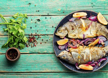 Soğan ve limonla kızartılmış balık. Kırsal ahşap masada pişmiş gökkuşağı alabalığı
