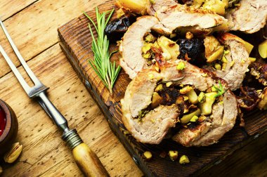 Fırında domuz eti, hurma, elma ve fıstık. Kesme tahtasında kızarmış yağsız domuz eti.