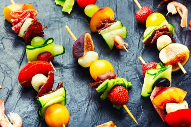 Açık büfe karides, jamon, meyve ve sebzeler ahşap şiş üzerinde.