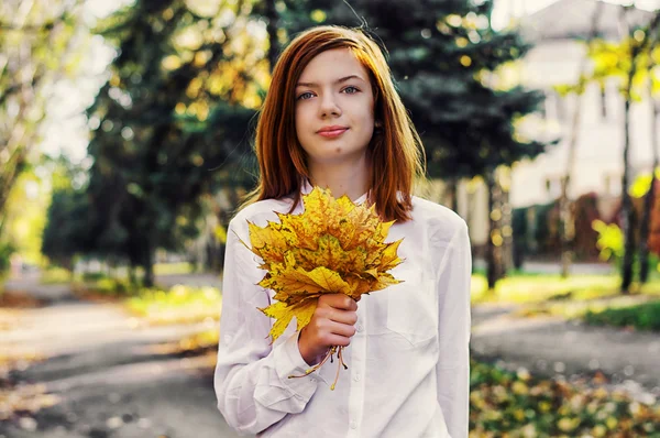 Девочка-подросток с осенними листьями в руках — стоковое фото