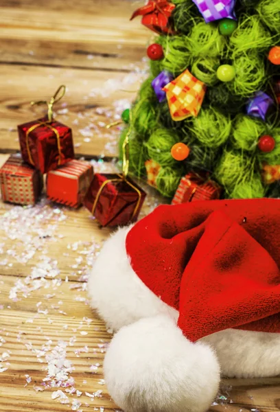 Рождественская шляпа на фоне елки с подарками — стоковое фото