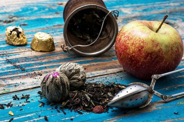 tea leaves and red apple on wooden background clipart