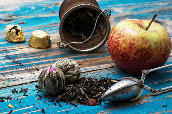 tea leaves and red apple on wooden background