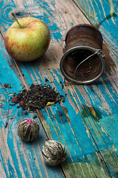 Tea leaves and red apple on wooden background — Stock Photo, Image