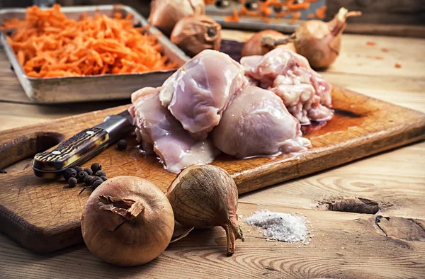 Cebolas em meio a pedaços de frango cru em um estilo rústico — Fotografia de Stock