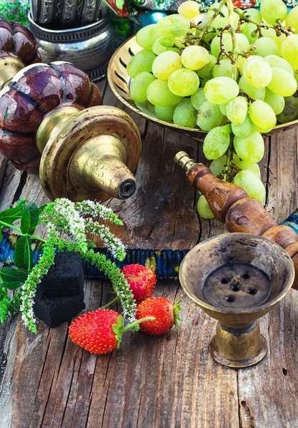 Hookah en medio de racimos de uvas y fresas — Foto de Stock