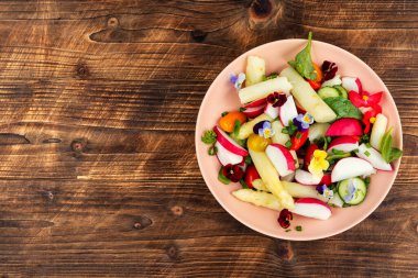 Vejetaryen salata kasesinde sebzeler ve yenilebilir çiçekler. Uzayı kopyala Metin için boşluk.