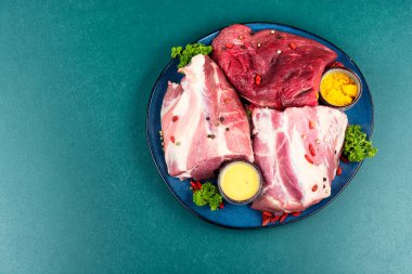 Et bir tabağa konur, baharatlar ve biberlerle süslenir. Yakınlarda baharatlı kaseler, kurutulmuş kırmızı biberler, taze otlar (maydanoz) ve bıçak bulunur..