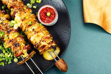 Potato and bacon skewers with cheese, sauces on a skewers, barbecue.
