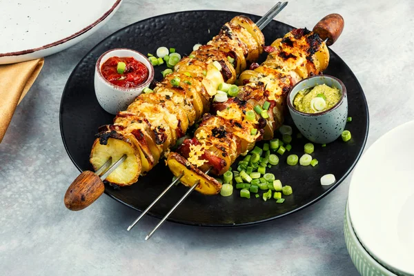 Potato and bacon skewers with cheese, sauces on a skewers, barbecue.