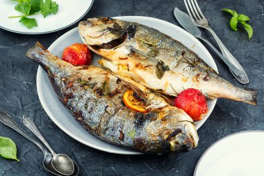 Dorado fish braised or baked with seasonal fruits on a concrete kitchen table.
