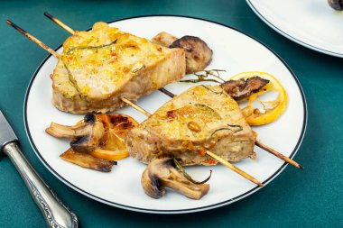 Baked tuna steak with vegetable garnish on skewers.
