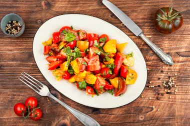 Renkli domatesli taze çiğ salata ve ahşap masa..