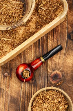 Köy ahşap masasında tütün bulunan ahşap pipo. Eski model. Pipo tütünü içiyorum.