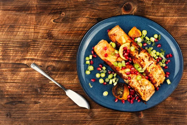 İki somon bifteği, soğan ve nar ile kızartılmış rustik ahşap masa. Paleo, Keto, Akdeniz yemekleri. Menü.