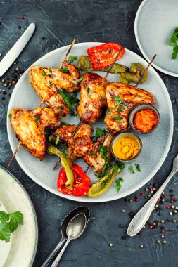 Izgarada pişirilip tabakta servis edilen şiş tavuk kanatları. Üst görünüm.