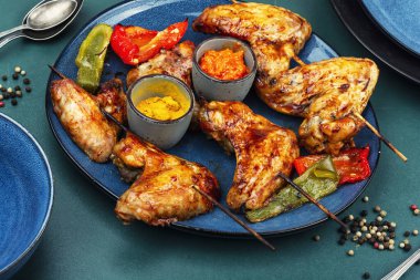 Şiş tavuk kanatları ızgarada pişirilir ve tabakta servis edilir..