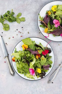 Yenilebilir çiçeklerle süslenmiş taze yeşil salata. Doğal malzemeli sağlıklı bitki temelli yemek..