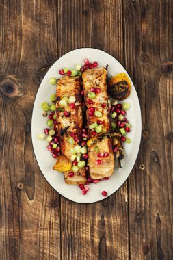 Kırmızı somon balığı bifteği, yeşil soğan ve ahşap arka planda nar tohumları..