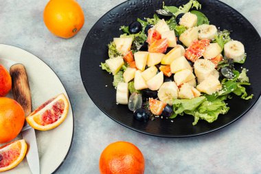 Taze mevsimlik meyvelerle yapılmış sağlıklı meyve salatası ve mutfak masasında servis edilir..