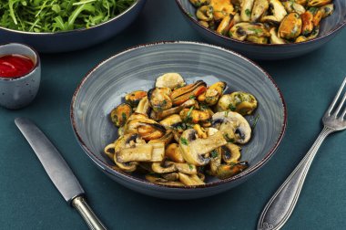 Hafif sarımsak soslu midyeli ve mantarlı sıcak salata. Ev yapımı deniz ürünleri yemeği..