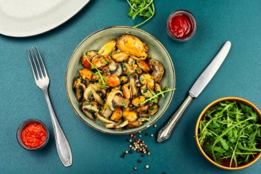 Bir tabak kızarmış midye, otlar ve kızarmış şampiyon mantarlarıyla süslenmiş. Üst görünüm.