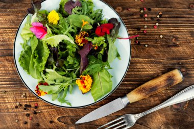 Yenilebilir çiçeklerle süslenmiş taze yeşil salata..
