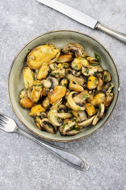 A plate of mussels in garlic sauce with roasted champignon mushrooms. Overhead view.