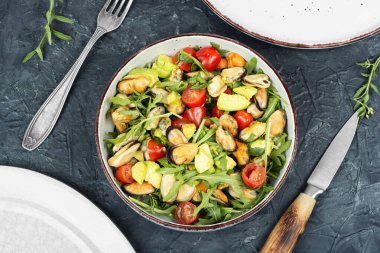 Tabakta sunulan yeşil yapraklı, midyeli ve karidesli taze deniz ürünleri salatası.