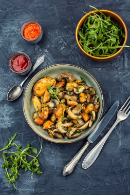 Bir tabak kızarmış midye, otlar ve kızarmış şampiyon mantarlarıyla süslenmiş. Yemek fotoğrafçılığı.