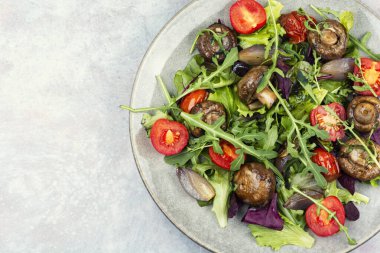 Bir tabak taze sebzeli ve yapraklı mantarlı kızarmış şampiyon mantarı. Boşluğu kopyala.