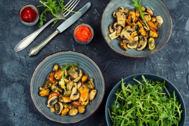 Temizlenmiş ve tavada kızartılmış midyeyle yapılmış salata ve sarımsak soslu şampiyon mantarı. Baharatlı deniz ürünleri sıcak salata ya da ana yemek olarak servis edilir..