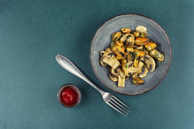 Bir tabak kızarmış midye, otlar ve kızarmış şampiyon mantarlarıyla süslenmiş. Metin için boşluk.