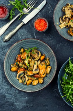 Temizlenmiş ve tavada kızartılmış midyeyle yapılmış salata ve sarımsak soslu şampiyon mantarı. Baharatlı deniz ürünleri sıcak salata ya da ana yemek olarak servis edilir..