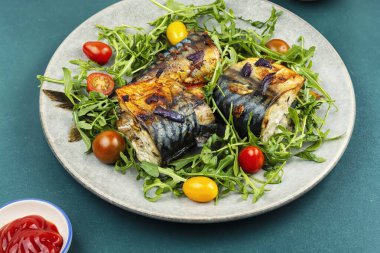 Yapraklı yeşillik ve domatesle servis edilen fırında uskumru, basit ve besleyici bir deniz mahsulü yemeği..