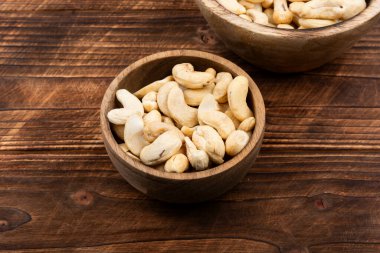 Mutfak masasındaki tabakta kaju fıstığı, çiğ kaju fıstığı. Sağlıklı atıştırmalıklar. Yemek fotoğrafçılığı.