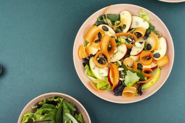 Taze elmalı organik salata kasesi, havuç bukleleri ve besleyici tohumlarla kaplı taze yeşillikler. Boşluğu kopyala.