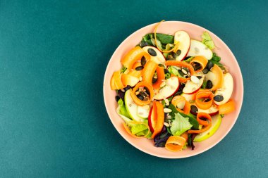 Dilimlenmiş elma, havuç kurdelesi, karışık yeşillik ve tohumdan yapılmış sağlıklı vejetaryen salatası. Boşluğu kopyala.