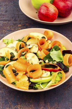 Taze elmalı organik salata kasesi, havuç bukleleri ve üzerine besleyici tohumlar konmuş taze yeşiller..