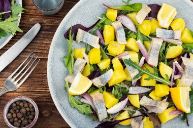 Taze ve besleyici salata, tuzlu ringa filetosu, haşlanmış patates, soğan ve yeşil yaprak tabakta servis edilir..