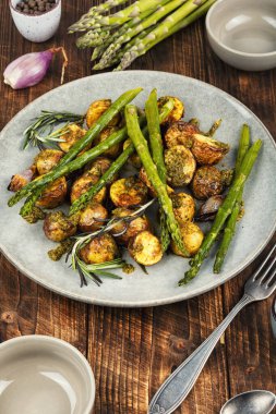 Fırında pişmiş, yeşil kuşkonmaz ve ahşap bir masada aromatik fesleğen pesto ile birlikte bebek patatesler. Sağlıklı vejetaryen yemeği.